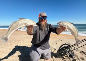 Ian from Tug Trash Outdoors carrying multiple fishing rods across a Florida beach using the Rod-Runner Portable Fishing Rod Caddy.